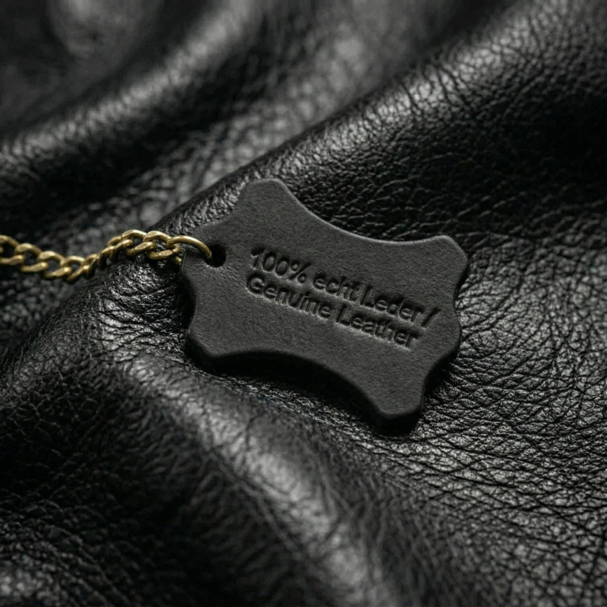100% echtes Leder – Detailaufnahme schwarzes Rindsleder mit Genuine-Leather-Siegel, Fronhofer Manufaktur