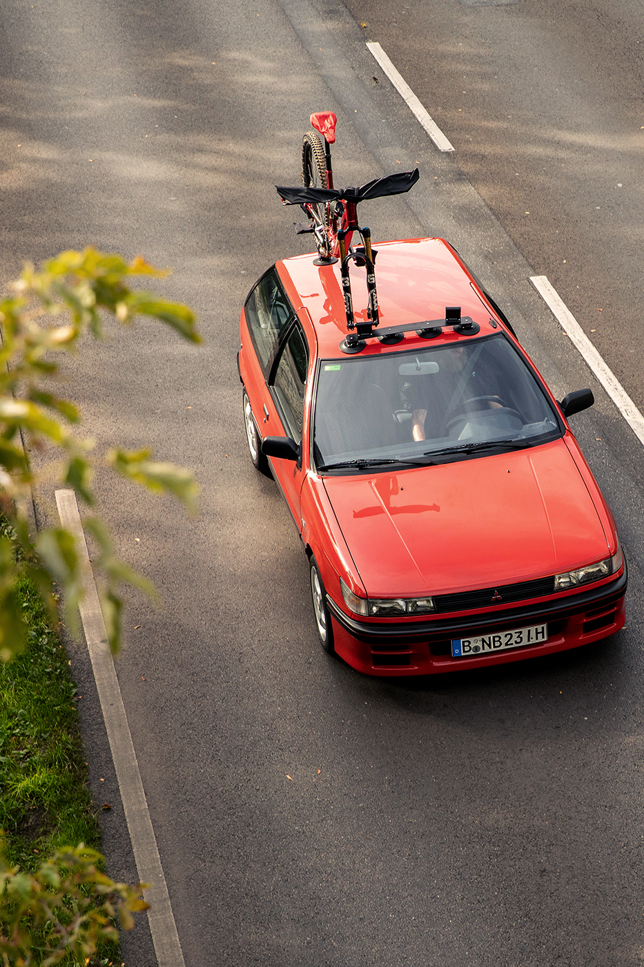 Bild zeigt e-Mountainbike (NICOLAI Saturn 14 Swift - TNS)	 auf Autodach eines 90er-Jahre Oldtimers (Mitsubishi Colt) - geschützt dank Lenkerhaube &	 Sattelkappe