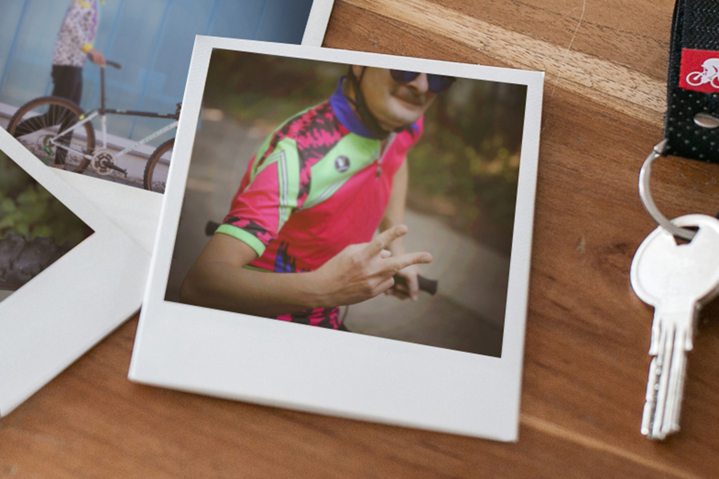 Bild zeigt Polaroids, von Toni in grün-blau-rotem Trikot und seinem Rocky-Mountain-MTB, auf Schribtisch