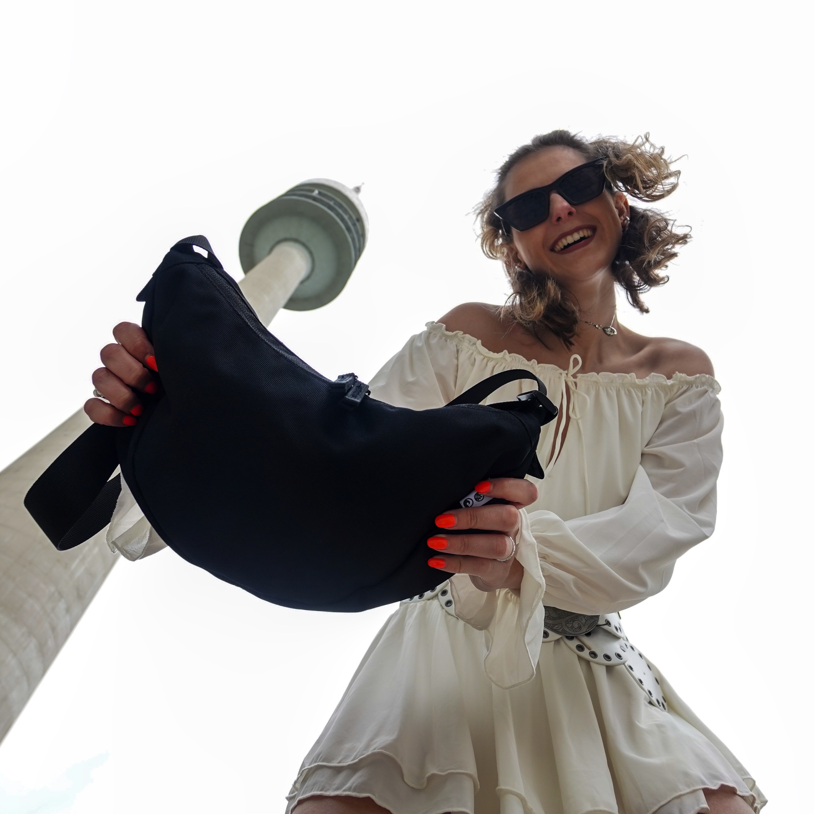 Sons of aloha Moon Bag Hoku in schwarz Outdoor Frau schaut nach unten in die Kamera und im Hintergrund ragt der Fernsehturm in die Höhe