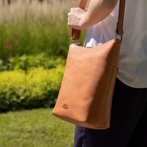 Sid & Vain Umhängetasche Damen hellbraun aus Leder Outdoor Frau traegt eine weite Leinenhose in blau und eine weiße Bluse