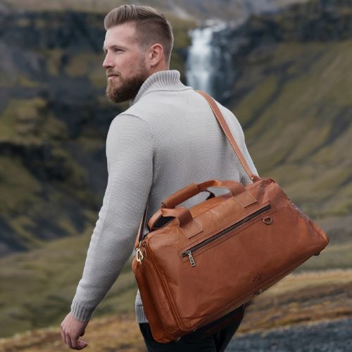 Sid & Vain Reisetasche Ziegenleder hellbraun Outdoor Mann steht an einem Wasserfall