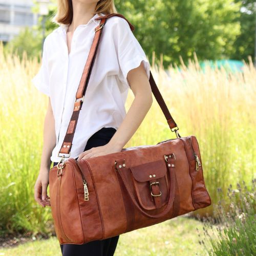 Sid & Vain Reisetasche Leder Ziegenleder hellbraun LANDON Frau traegt eine weiße kurzarmige Bluse und eine schwarze Hose