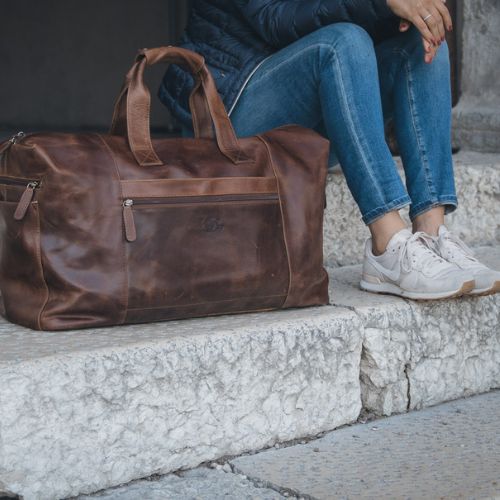 Sid & Vain Reisetasche Leder Outdoor Frau sitzt auf einer Treppe daneben steht die Reisetasche