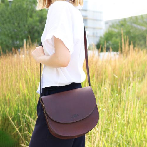 Sid & Vain Schultertasche Leder Frau steht an einer Wiese und traegt die Tasche über der Schulter