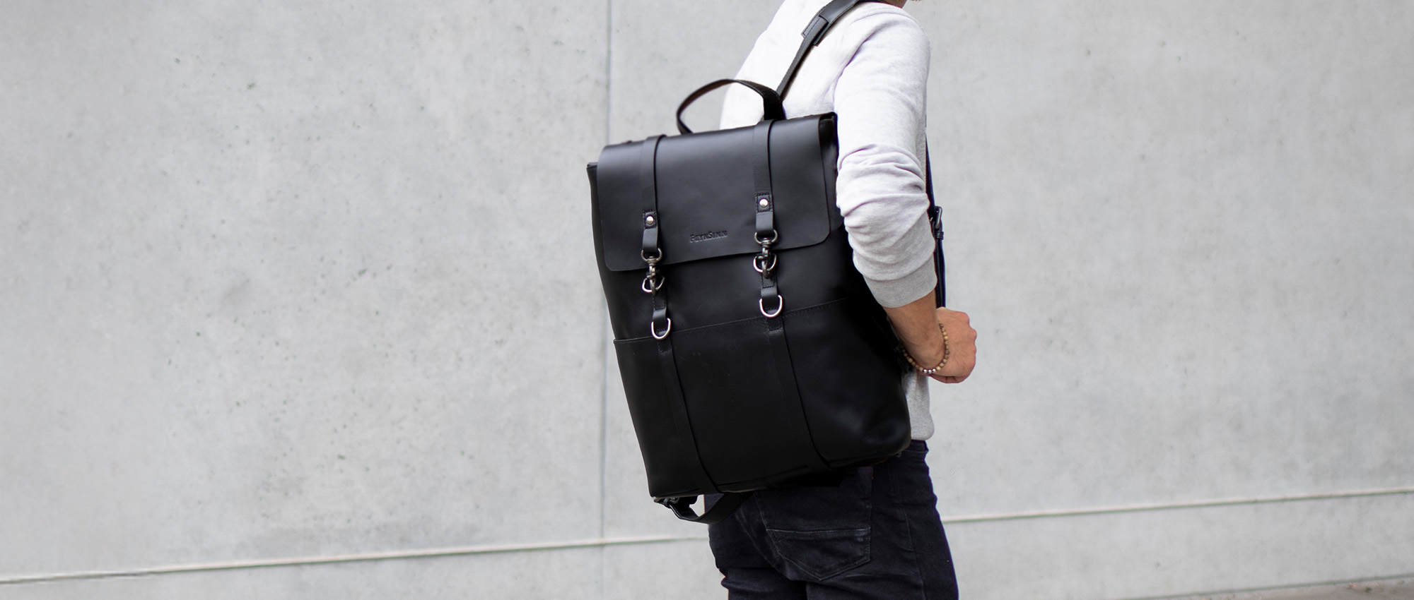 Laptop Rucksack Herren in schwarz an Mann vor Wand