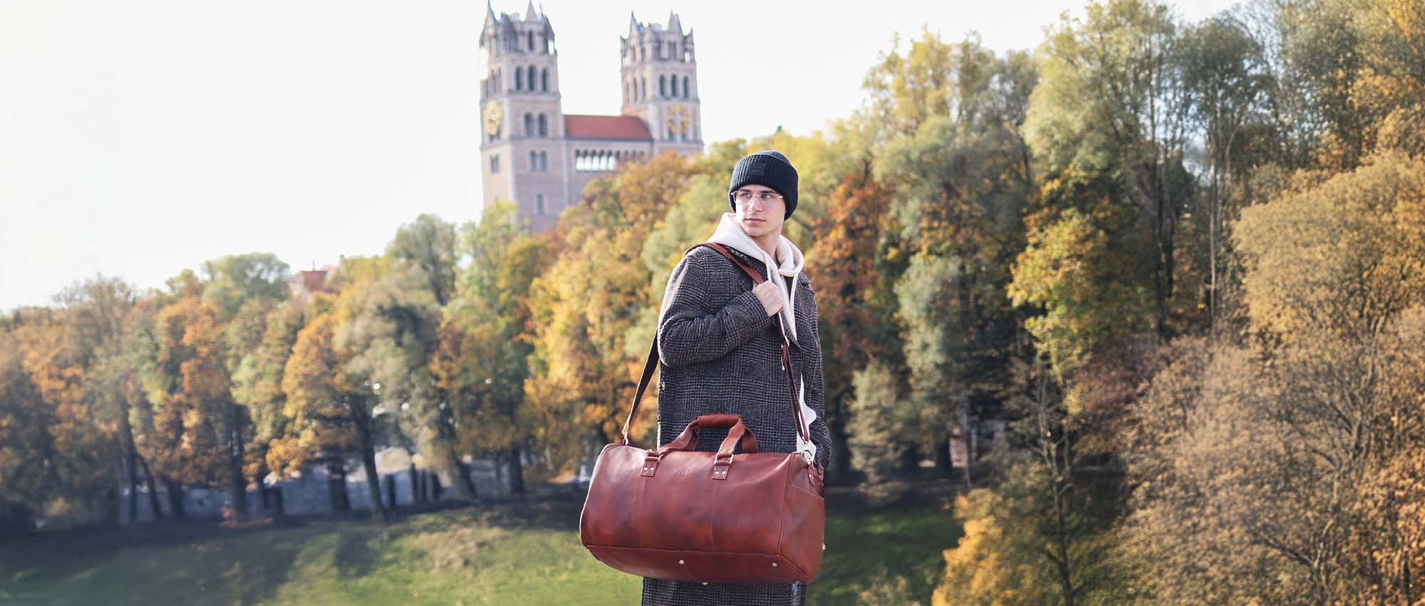 leather travel bag on the shoulder of a man in a smart casual look