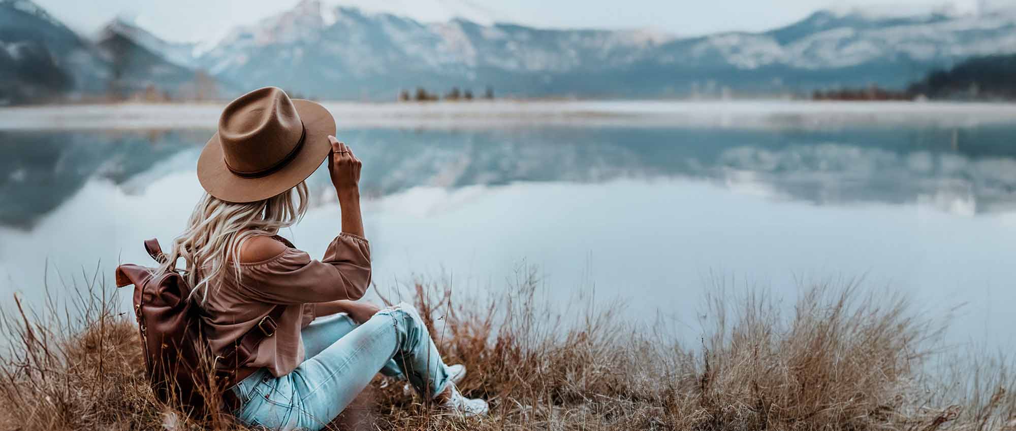 Women's brown leather backpack, woman sitting by a lake