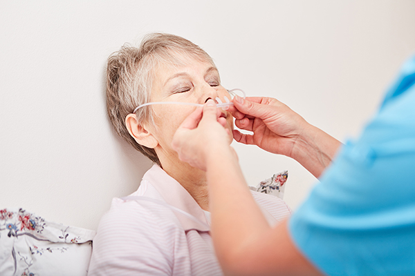 Eine Pflegekraft in blauem Hemd justiert die Silikon-Nasenbrille bei einer älteren Patientin, um die korrekte Anwendung zu gewährleisten.