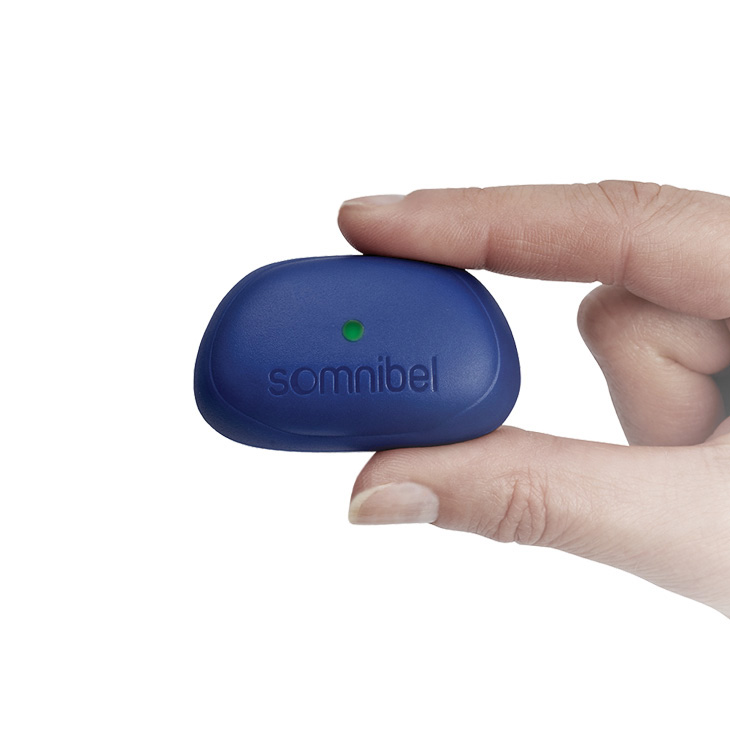 Nahaufnahme eines kleinen, blauen Somnibel Schlafpositionstrainers, der in einer Hand gehalten wird.