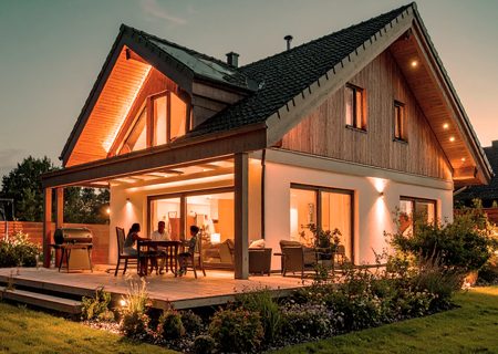 Freistehendes Einfamilienhaus mit beleuchtetem Garten am Abend