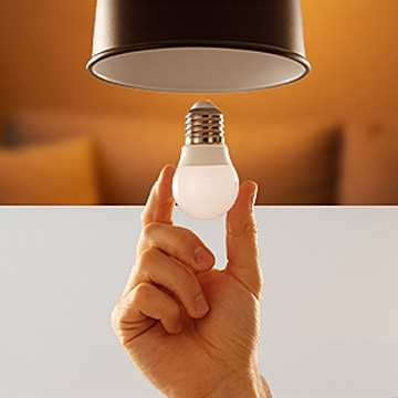 Hand mit LED Leuchtmittel, das in einer Leuchte installiert wird