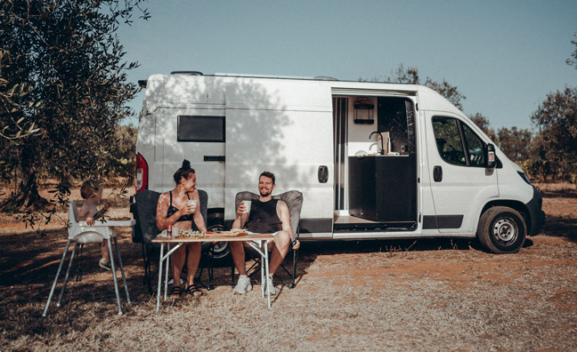 Familie sitzt vor Campervan