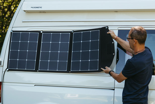 Mann hängt Solartasche an Campervan