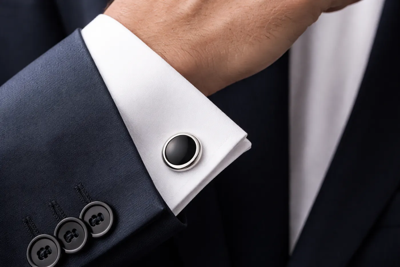 Manschettenknopf an weißer Hemdmanschette mit dunklem Businessanzug