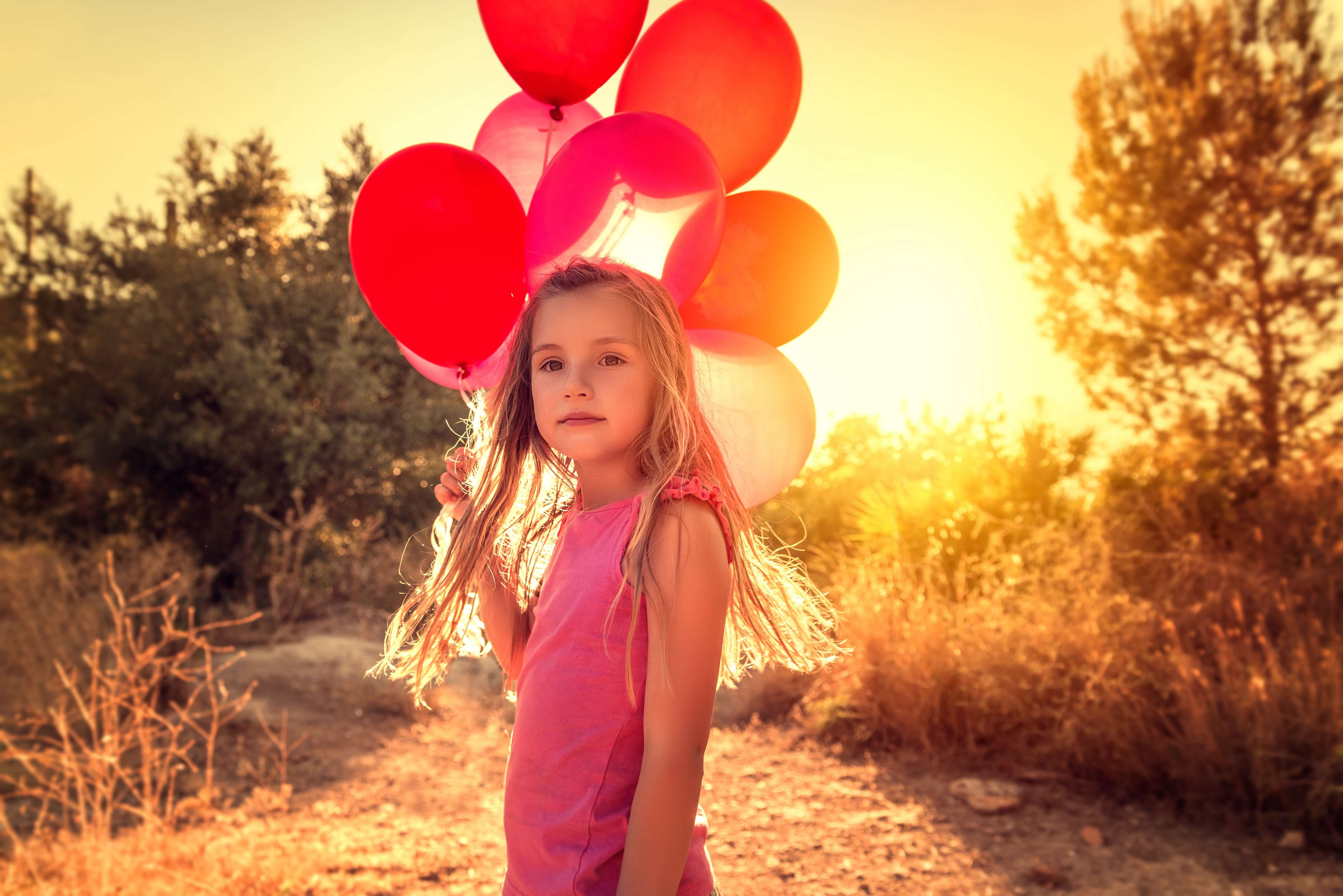 Mädchen mit Luftballons in der Hand im Sonnenschein
