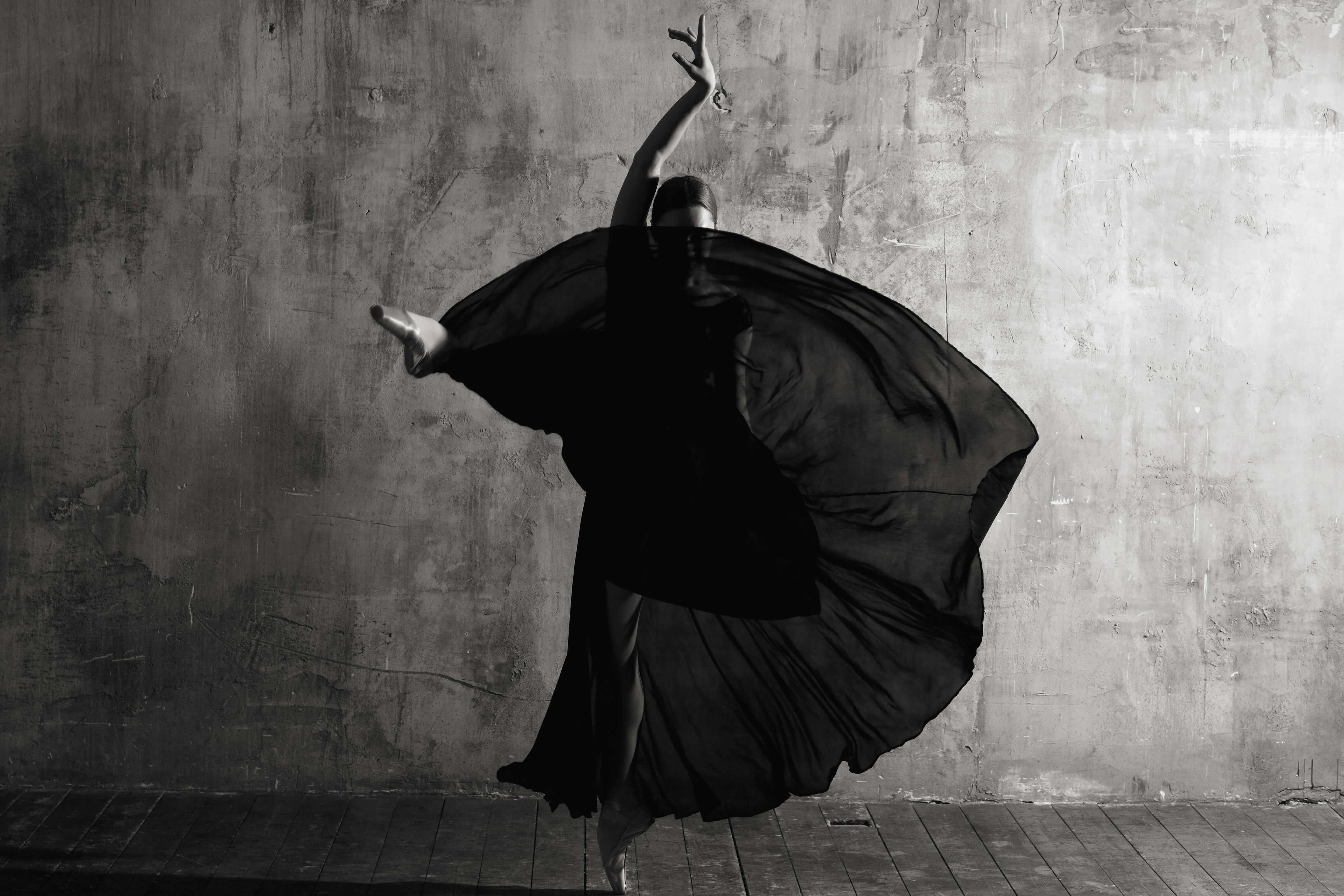Schwarz-Weiß-Aufnahme einer Balletttänzerin in schwarzem Kleid und Fächer (posiert ausdrucksstark)
