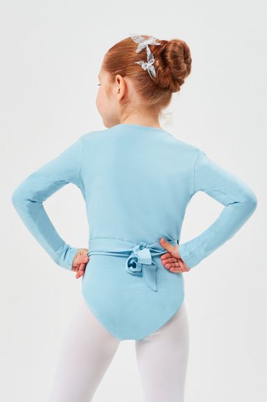 Ein junges Mädchen in einem blauen Ballettbody und weißen Strumpfhosen steht mit den Händen in den Hüften