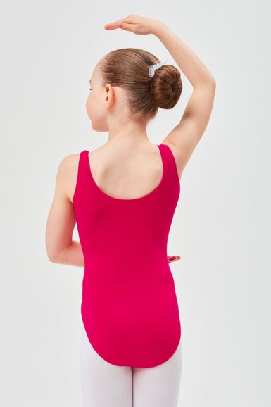 Ein junges Mädchen in einem rosa Ballettbody und weißen Strumpfhosen steht in einer Ballettpose