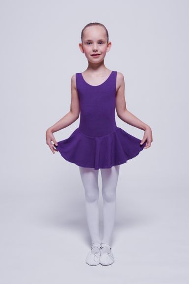 Ein junges Mädchen in einem lila Ballettbody und weißen Strumpfhosen steht in einer Ballettpose.