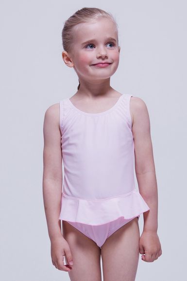 Junges Mädchen in einem hellrosa Badeanzug mit Rüschenrock steht.