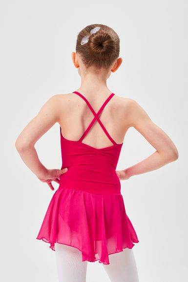 Ein junges Mädchen in einem rosa Ballett-Outfit steht mit den Händen in den Hüften und blickt von der Kamera weg.