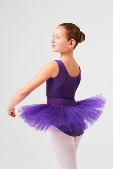 Junges Mädchen in einem lila Ballettbody und Tutu posiert in einer Ballettposition.