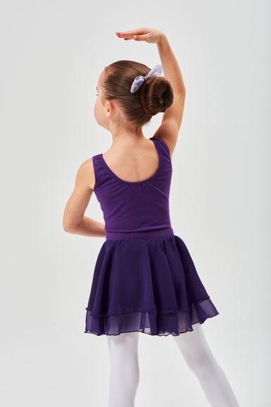 Junges Mädchen in einem lila Ballett-Outfit posiert mit einem erhobenen Arm