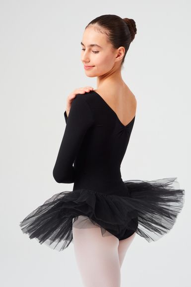 Eine Ballerina in einem schwarzen Ballettbody und Tutu posiert mit einer Hand auf ihrer Schulter und blickt über ihre Schulter.