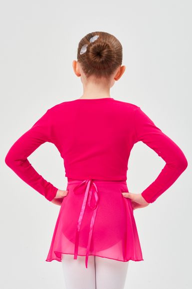 Ein junges Mädchen in einem leuchtend rosa Ballett-Outfit steht mit den Händen in den Hüften und blickt von der Kamera weg.
