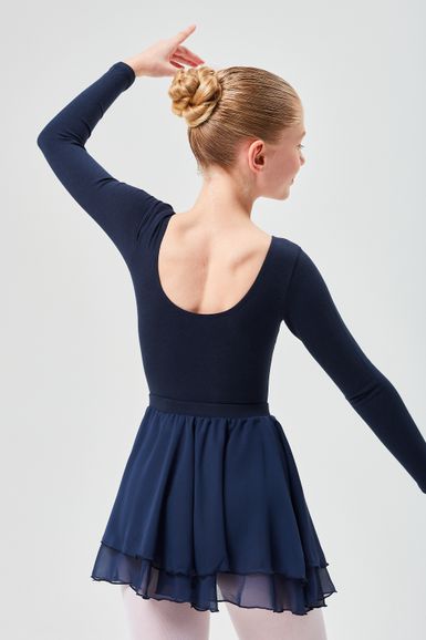 Eine Balletttänzerin in einem marineblauen Ballett Trikot und Rock posiert mit einem erhobenen Arm und zeigt eine ordentliche Duttfrisur.