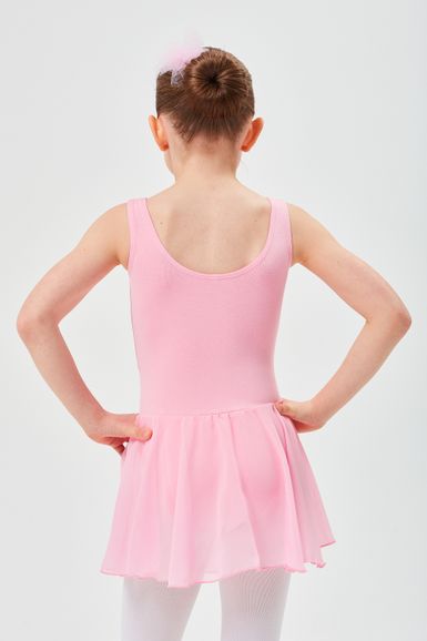 Ein junges Mädchen in einem rosa Ballett-Outfit steht mit den Händen in den Hüften und blickt von der Kamera weg.