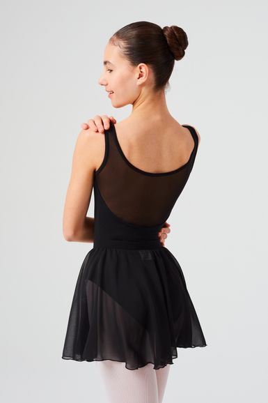 Eine junge Balletttänzerin in einem schwarzen Ballett Trikot und Rock steht mit einer Hand auf der Schulter und blickt abgewandt.