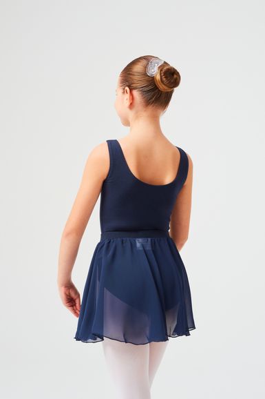 Ein junges Mädchen in einem marineblauen Ballett Trikot und Rock steht mit abgewandtem Gesicht da