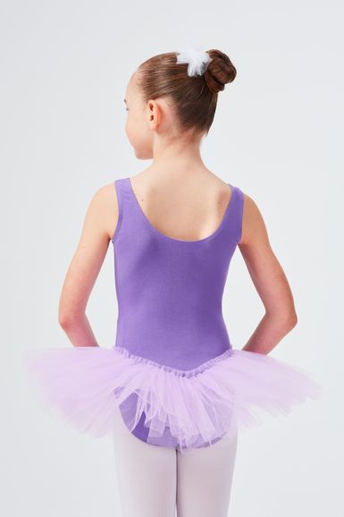 Ein junges Mädchen in einem lila Ballett Trikot und Tutu steht mit dem Rücken zur Kamera