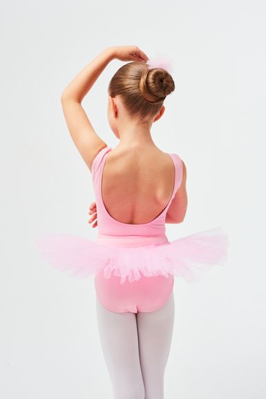 Ein junges Mädchen in einem rosa Ballettbody und Tutu steht mit dem Rücken zur Kamera