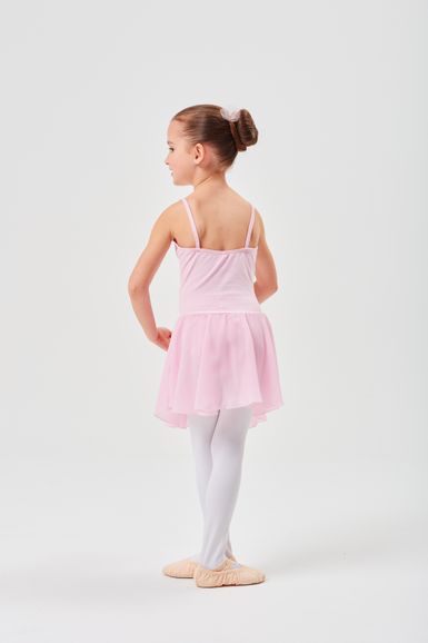 Ein junges Mädchen in einem rosa Ballett-Outfit und weißen Strumpfhosen steht in einer Ballettpose und blickt von der Kamera weg.