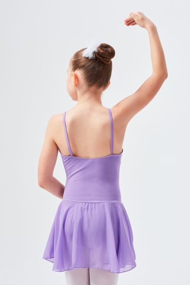 Junges Mädchen in einem lavendelfarbenen Ballettkleid posiert mit erhobenem Arm