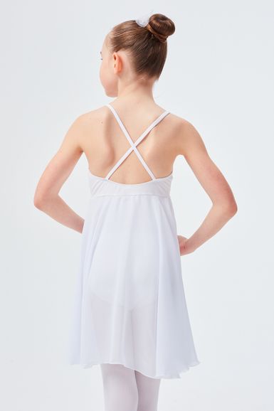Ein Mädchen in einem weißen Tanzkleid mit gekreuzten Trägern steht mit dem Rücken zur Wand.