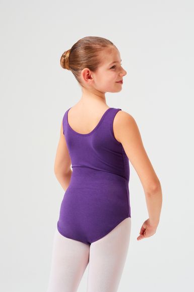 Ein Mädchen in einem lila Ballett Trikot und weißen Strumpfhosen steht mit dem Rücken zu ihr und blickt über ihre Schulter.