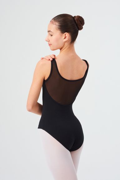 Eine Ballerina in einem schwarzen Ballett Trikot und weißen Strumpfhosen steht mit dem Rücken zu ihm und blickt über ihre Schulter.