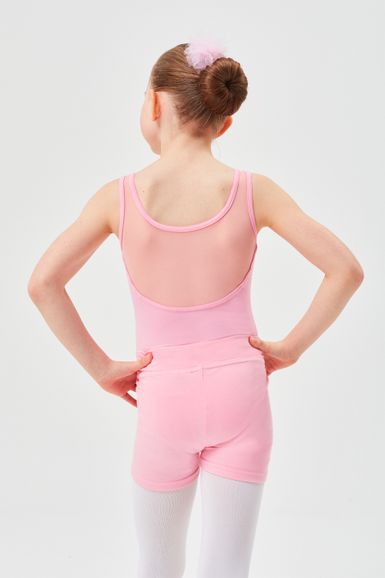 Ein junges Mädchen in einem rosa Ballett-Outfit steht mit den Händen in den Hüften und blickt von der Kamera weg.