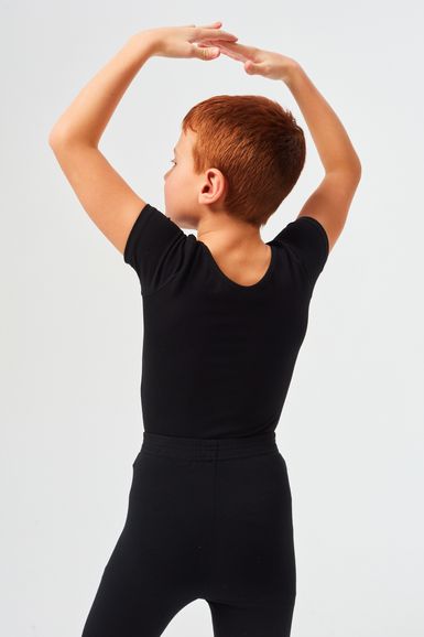 Ein Kind in schwarzer Tanzkleidung steht mit über dem Kopf erhobenen Armen