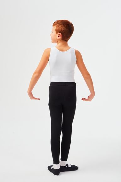Ein kleiner Junge in einem weißen Tanktop und schwarzen Leggings steht in einer Ballettpose.