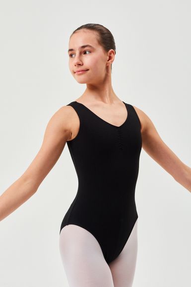 Eine Person in einem schwarzen Ballett Trikot und weißen Strumpfhosen steht mit ausgestreckten Armen da und blickt zur Seite.