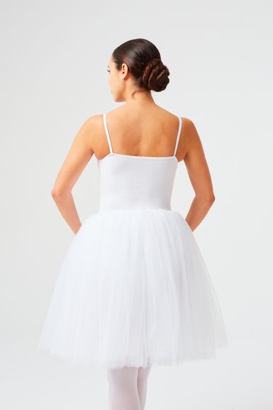 Eine Frau in einem weißen Ballettkostüm steht mit dem Rücken zur Kamera.