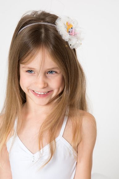 Junges Mädchen mit langen hellbraunen Haaren trägt ein weißes Kleid und einen Haarreif.