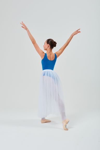 Eine Balletttänzerin in einem blauen Trikot und einem weißen Tutu posiert mit erhobenen Armen.