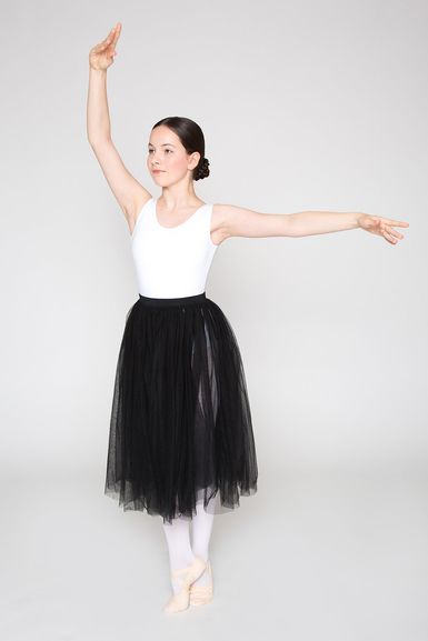 Balletttänzerin in einem weißen Trikot und einem schwarzen Tüllrock posiert mit erhobenen Armen.