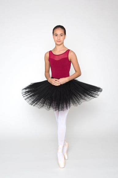Eine Balletttänzerin in einem kastanienbraunen Trikot und einem schwarzen Tutu posiert auf Spitze.